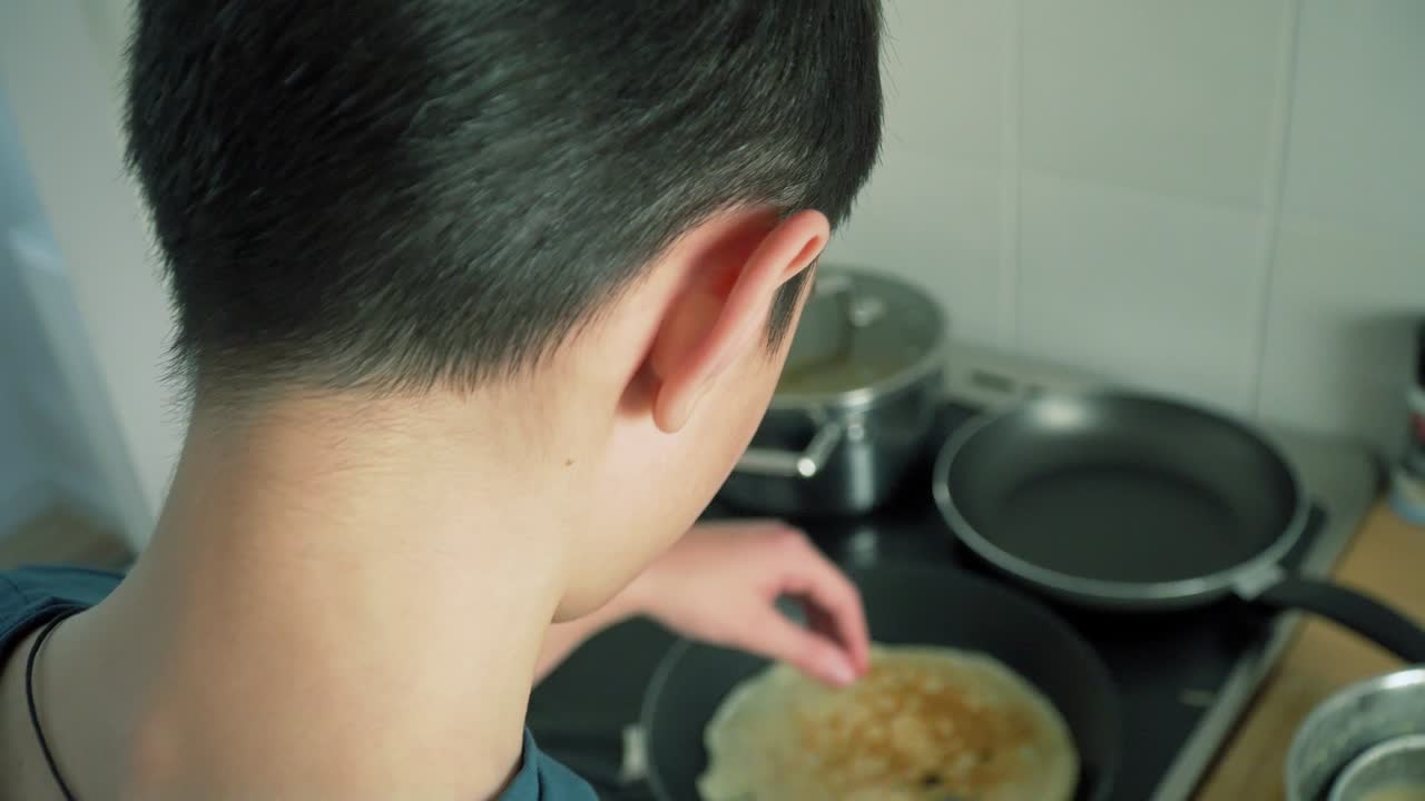 우크라이나 출신의 난민 소년은 호텔 렌트 객실의 부에서 팬케이크를 요리하고 있습니다.