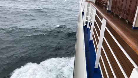 Slow-motion,-downward-view-of-the-spraying,-rolling-water-off-the-left,-port-side-of-a-cruise-ship