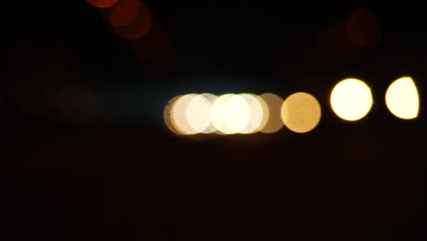 steady stream of car headlights out of focus traveling toward the viewer, bokeh balls, blurred lights, dark tunnel