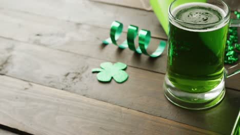 Video-of-st-patrick's-green-shamrock-and-green-beer-with-copy-space-on-wooden-background