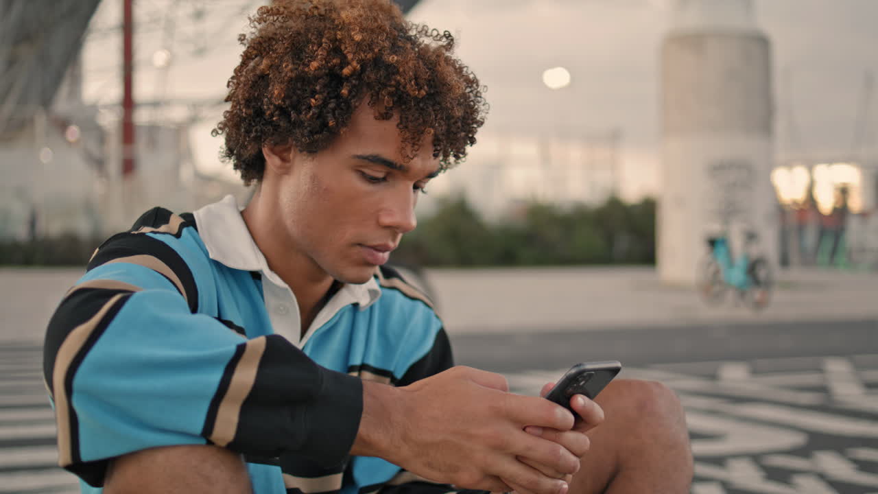 Focused hipster texting smartphone evening city. Teen use mobile phone closeup
