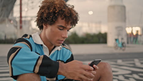 focused hipster texting smartphone evening city. teen use mobile phone closeup