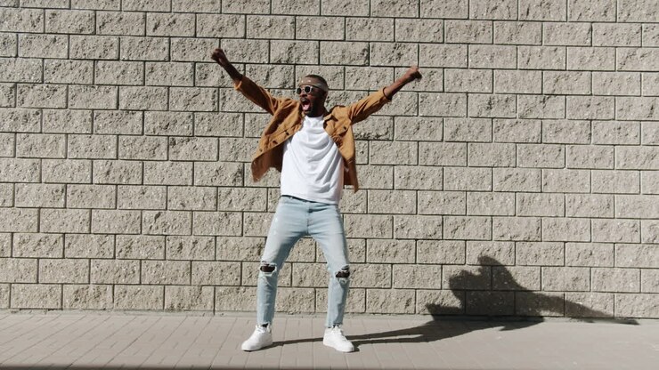 Man Dancing in Front of a Brick Wall