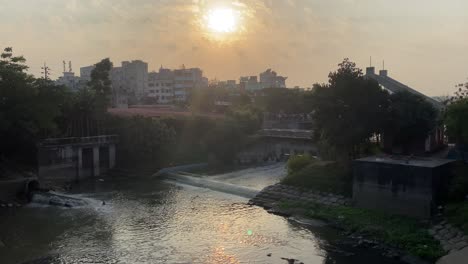 孟加拉達卡城市區的<unk>色河水道上的日落天空