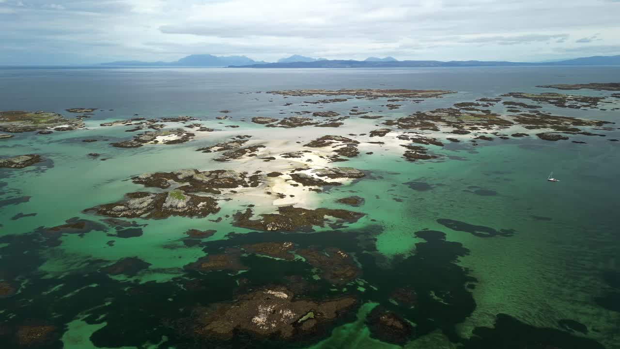 Aerial drone view of Arisaig skerries and small yacht, pan, Scotland