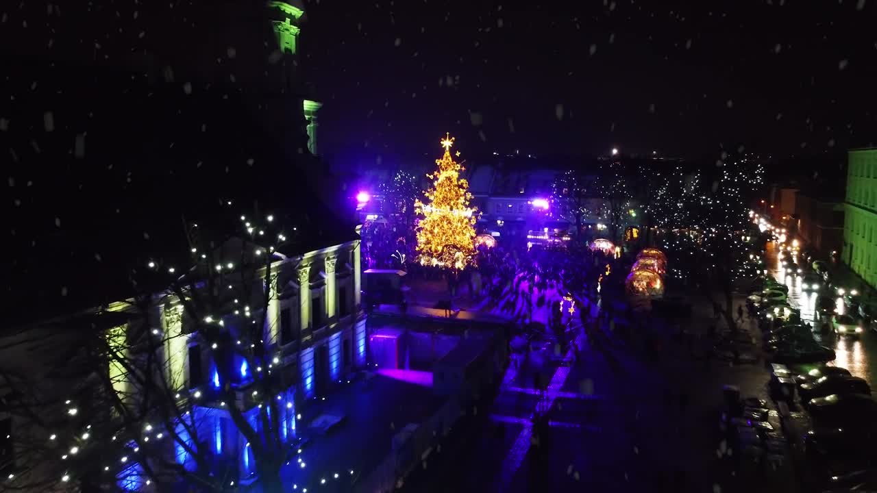 Vibrante árbol de Navidad de Kaunas durante una nevada, vista aérea con avance.