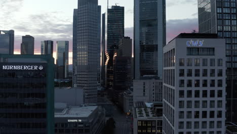 AERIAL:-Slow-Forward-Flight-through-Frankfurt-am-Main,-Germany-Skyline-Skyscraper-Canyon-in-Purple-Sunset-Light--in-June-2020