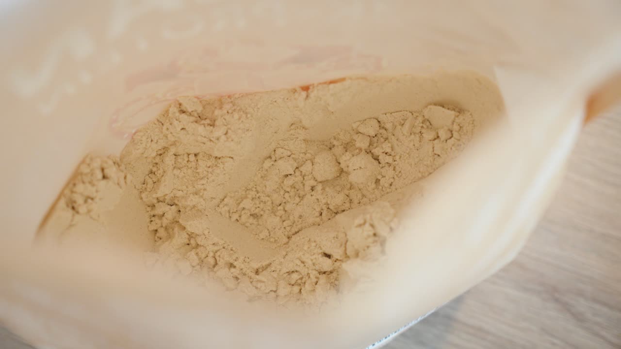 close-up shot of multiple servings of protein powder being taken from a package