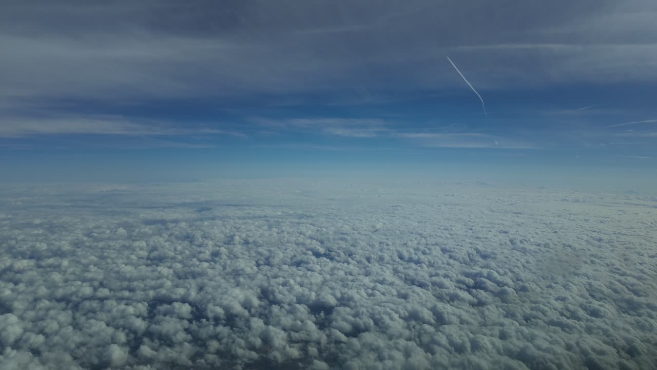 an immerasive pilot’s view from a jet cockpit while flying at supersonic speed at very high altitude over an endless sea of cottony clouds.