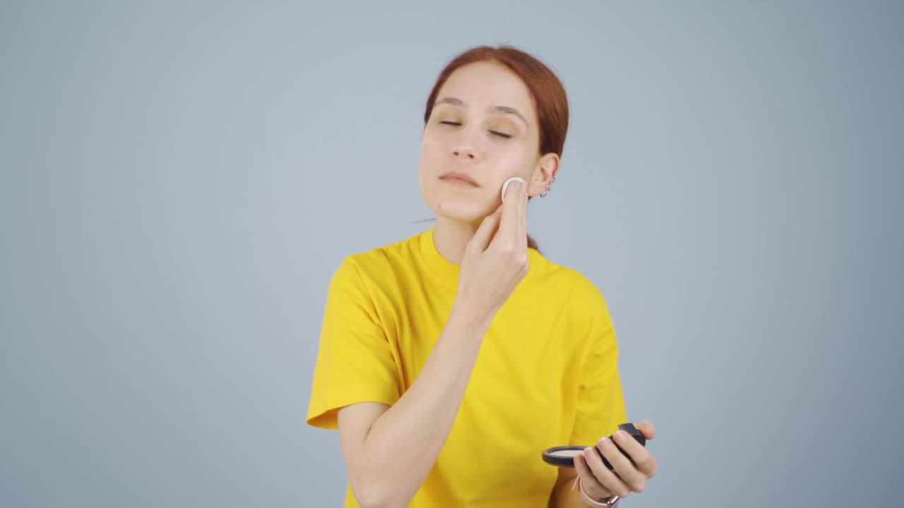 la mujer que se pone polvo en la cara. se está maquillando.