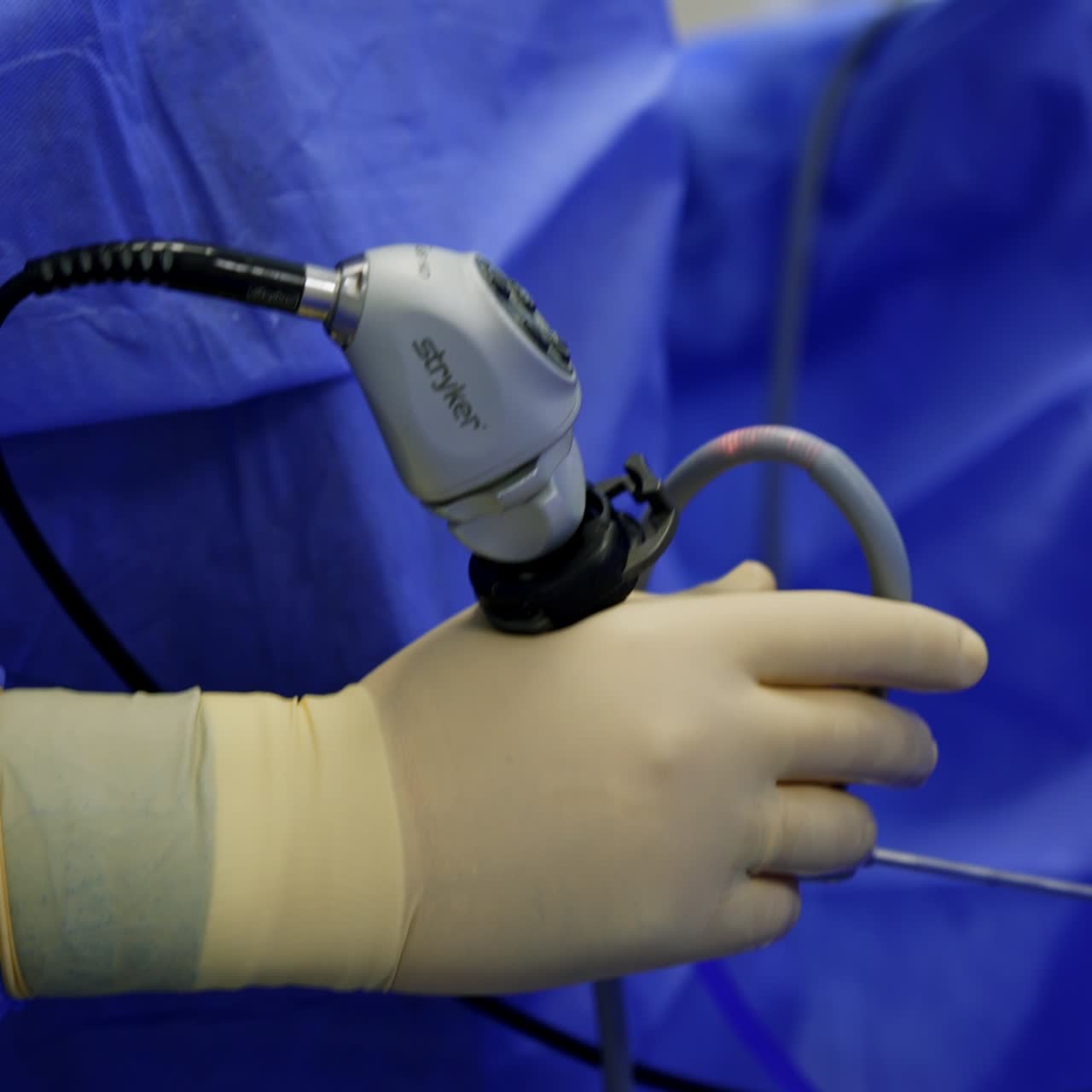 Unknown male surgeon holding a modern electric surgical tool. Doctor carries out operation using innovative instruments. Side view close up. Vertical screen