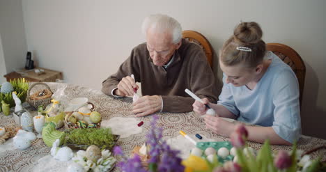 senior man and woman painting easter eggs