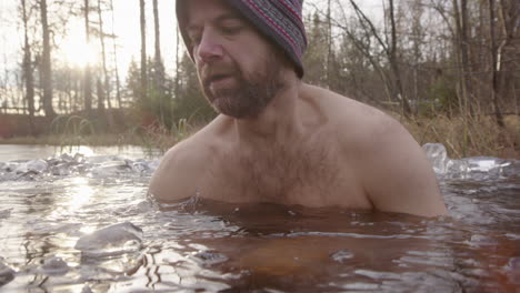 Un-Apuesto-Hombre-Barbudo-Se-Sienta-En-Un-Pozo-De-Baño-En-Un-Lago-Congelado