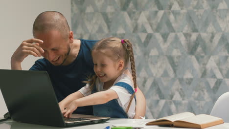 father and girl have fun doing homework on computer in room