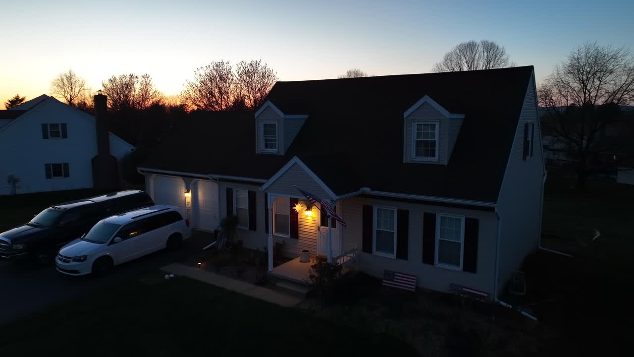 Aerial approaching shot of one family house with american flag during golden sunset