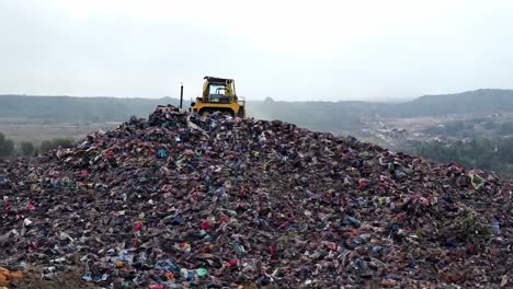 large pile of garbage with a bulldozer on top