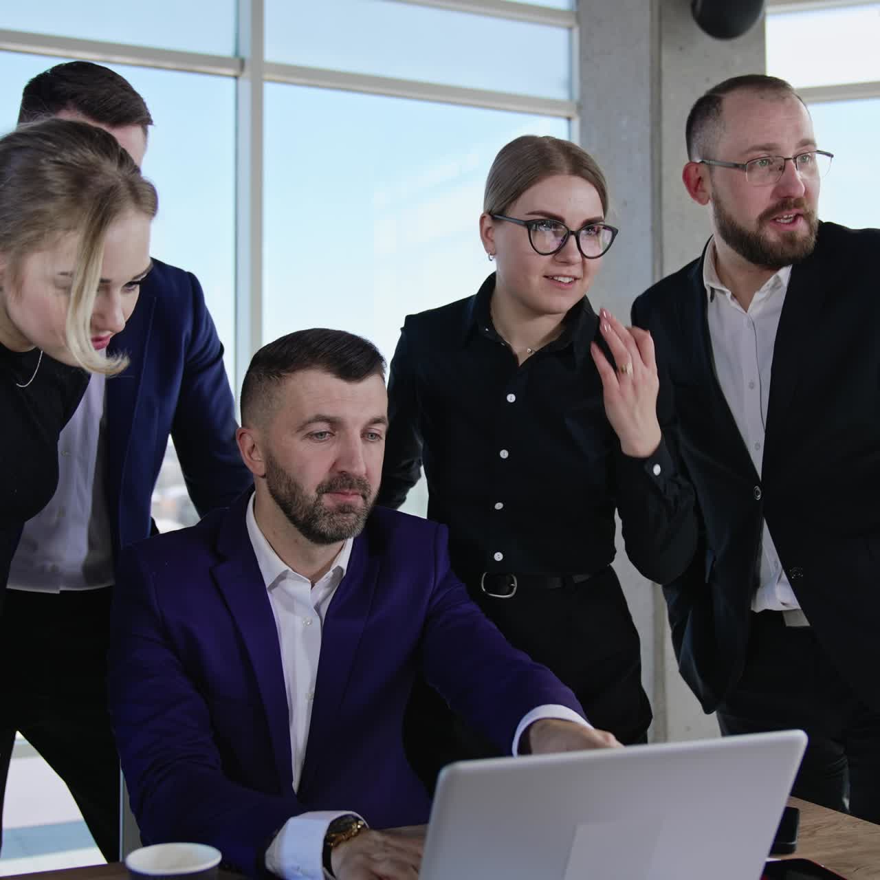 Businessman sits at the computer surrounded by his employees. Teammates sharing ideas and communicating for the best result