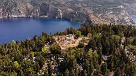 Antiguo-Fuerte-En-La-Cima-De-La-Colina-Verde-En-El-Pueblo-De-Assos-En-Kefalonia,-Islas-Jónicas,-Grecia---Toma-Aérea