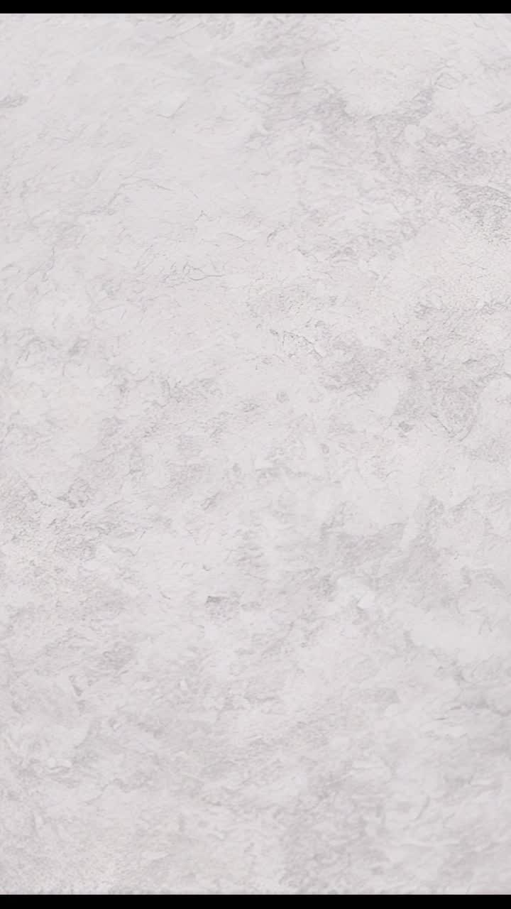 Vertical video: Playing camera footage showing gray plaster wall indoors for background texture