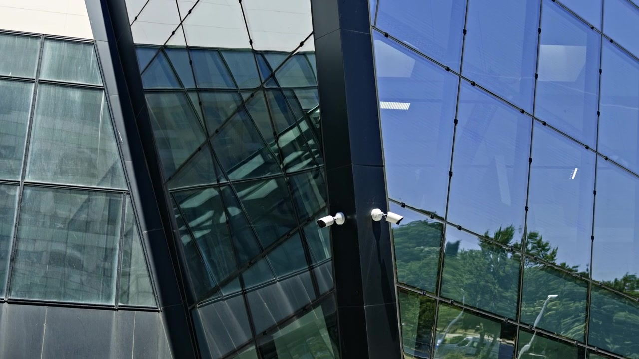 Edificio con ventanas de cristal que reflejan la luz en una concurrida zona urbana durante las horas del día.