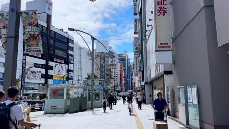 people walking through a busy commercial street in tokyo on a sunny day