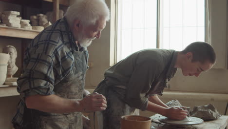 young woman learning pottery with senior teacher