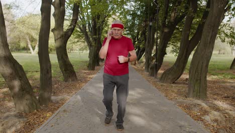 Hombre-Mayor-Corriendo-En-El-Lugar-En-El-Parque.-Hombre-Corredor-Maduro-Entrenando,-Escuchando-Música