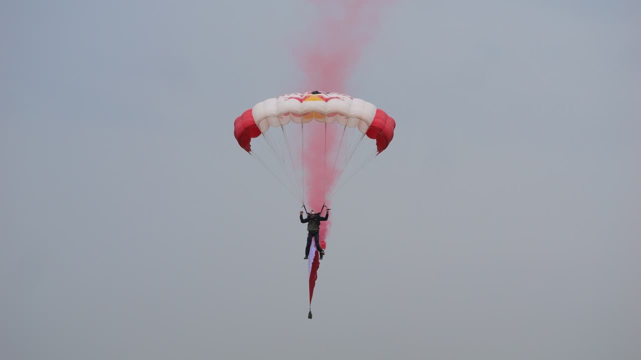 Parachute jumpers landing with smoke at the Airpower 2024 event in Austria.