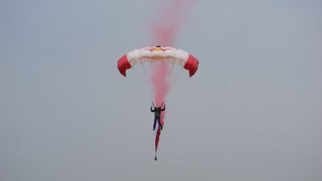 parachute jumpers landing with smoke at the airpower 2024 event in austria.