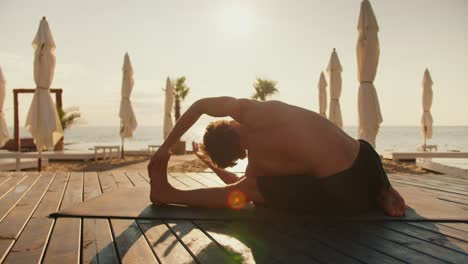 The-guy-is-stretching-and-doing-stretching-on-a-sunny-beach-in-the-morning.-Morning-exercise-for-health