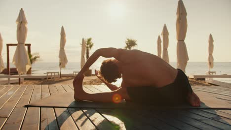 the guy is stretching and doing stretching on a sunny beach in the morning. morning exercise for health
