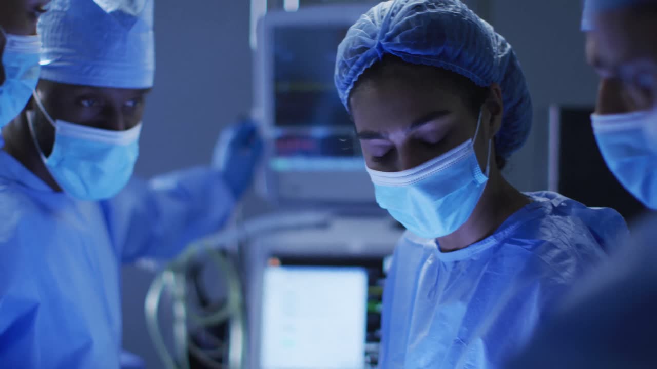 Mixed race surgeons wearing protective clothing discussing in operating theatre
