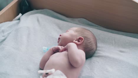 newborn baby with short blond hair and pacifier in mouth