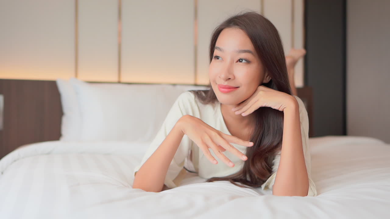 아름다운 아시아 소녀는 침대에 누워 휴식을 취합니다. 슬로우 모션