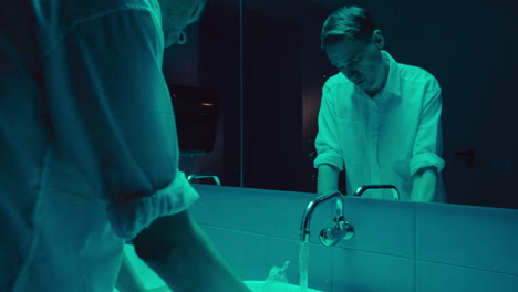 man washing hands in a bathroom at night