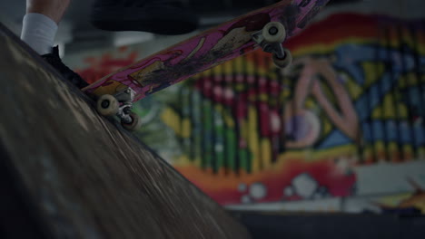 el patinador deportivo comienza a montar en patineta en la rampa en el parque de patinaje con graffiti.