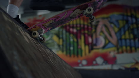 sporty skater start riding on skateboard in ramp at skate park with graffiti.