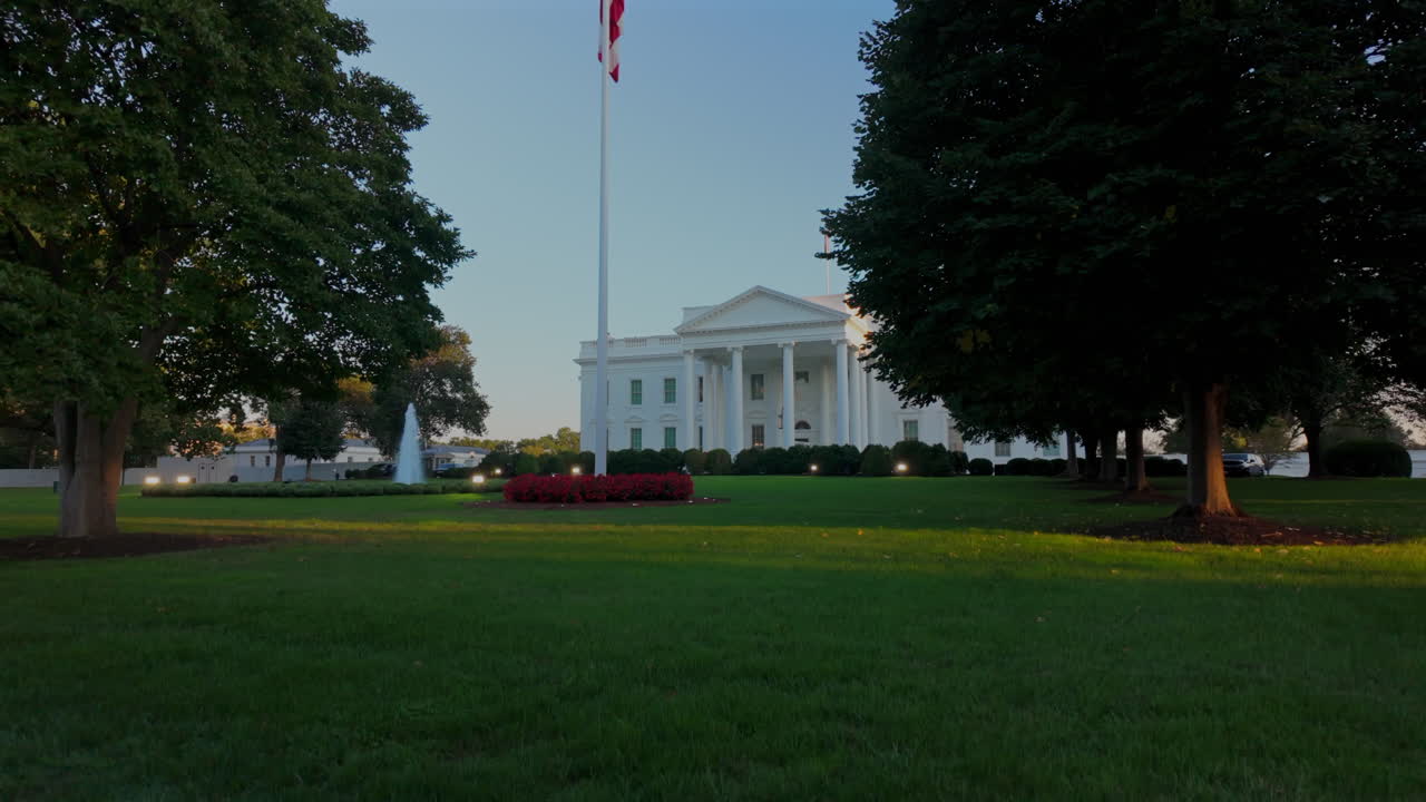 Distant view of the White House behind green lawn and trees, Washington DC