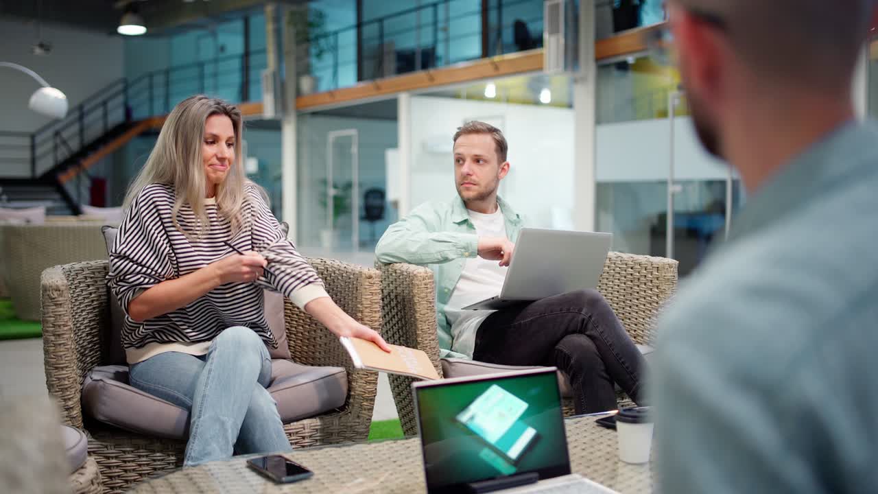 joven equipo de negocios de inicio de tres sentados en la sala de la oficina y discutiendo la estrategia en la reunión. gerente femenina explicando ideas, sus colegas masculinos con computadoras portátiles escuchando