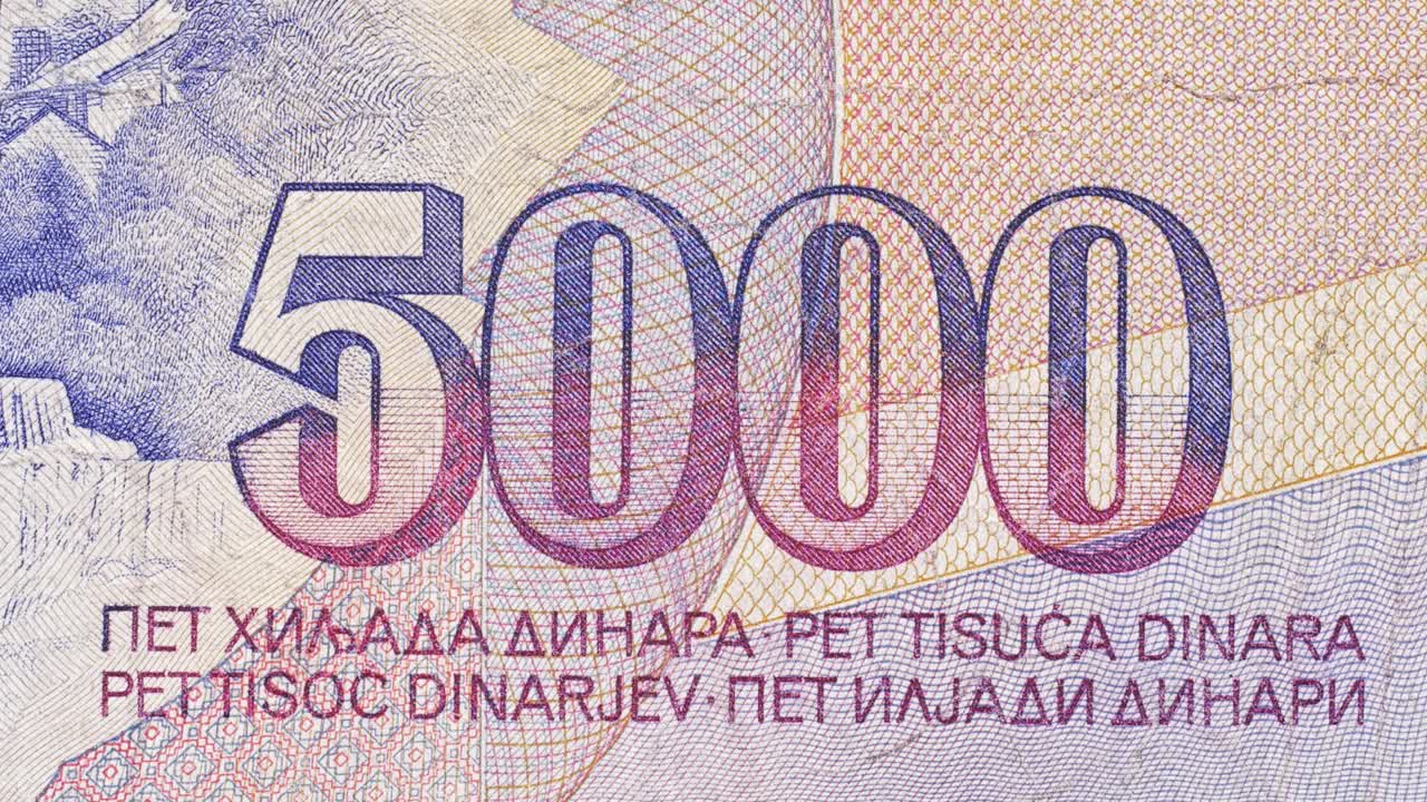 Tilt macro over a 5000 dinar Yugoslav banknote, highlighting the large numeral and lines of text in multiple languages