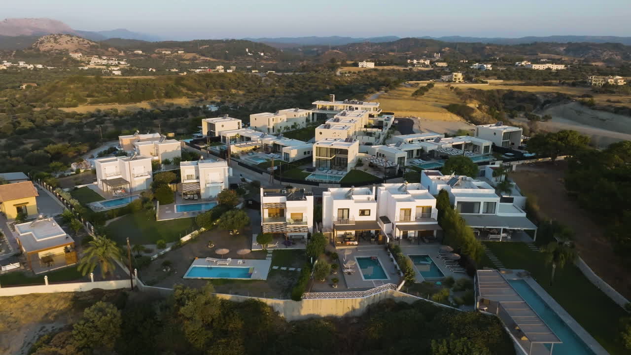 Panoramic drone shot circling a holiday resort village, golden hour in Greece