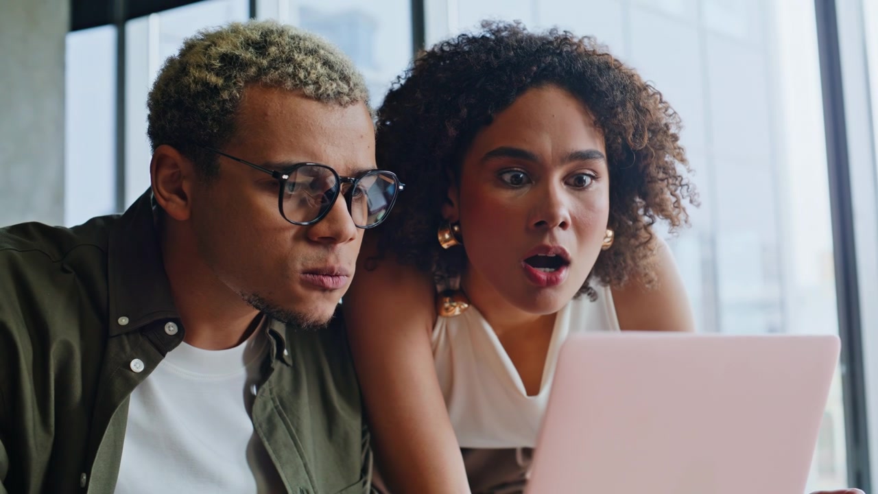 Frustrated business partners reacting to bad news on laptop in office meeting