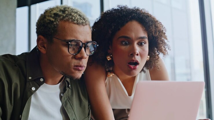 Frustrated business partners reacting to bad news on laptop in office meeting