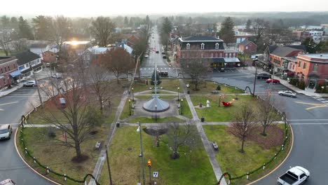 Toma-De-Drones-En-Ascenso-De-Un-Parque-Circular-Rodeado-De-Una-Rotonda-Con-Autos-Conduciendo