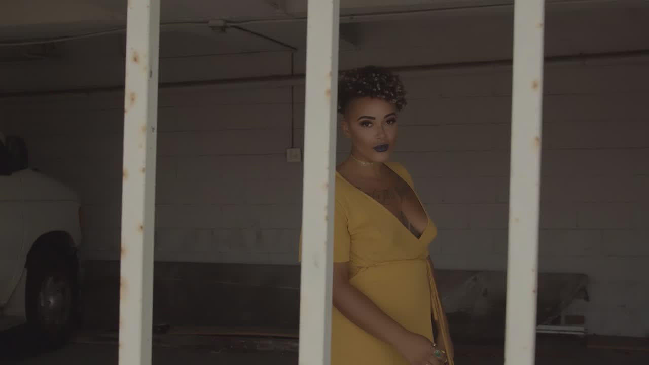 Bellissima modella di colore in abito giallo in posa per la macchina fotografica