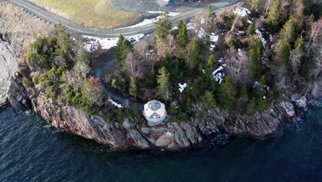 glass eco house on top of rocky cliffs by the shore in norway