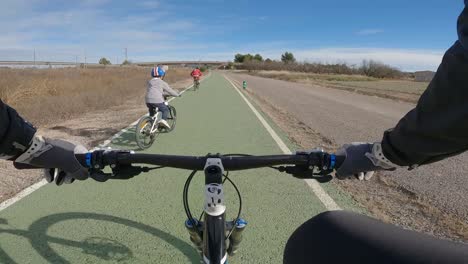 two little brothers riding with their father on a bike path