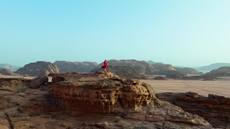 Circling-Over-Woman-Standing-On-Sandstone-Rock-Formations-In-Jordan,-Wadi-Rum-Protected-Area