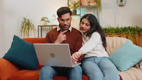 happy young diverse couple family discussing planning together booking while using laptop at home
