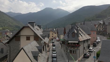 A-mesmerizing-drone-ascent-from-a-quaint-neighborhood-unveils-the-scenic-Spanish-town-nestled-in-the-Pyrenees-mountains,-with-majestic-mountain-vistas-and-beautiful-clouds-in-the-distance